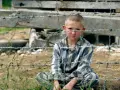 Pojken i randig pyjamas, Shmuel, sitter bakom taggtråd. Hans ansikte är smutsigt och hans blick är sorgsen.