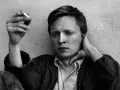 En man med cigarett i handen, Stig Larsson, med handen bakom nacken.