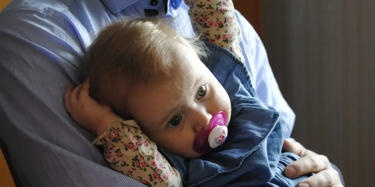 En pappa håller sin lilla dotter, som har en napp i munnen. Bilden känns som en dikt till min dotter.
