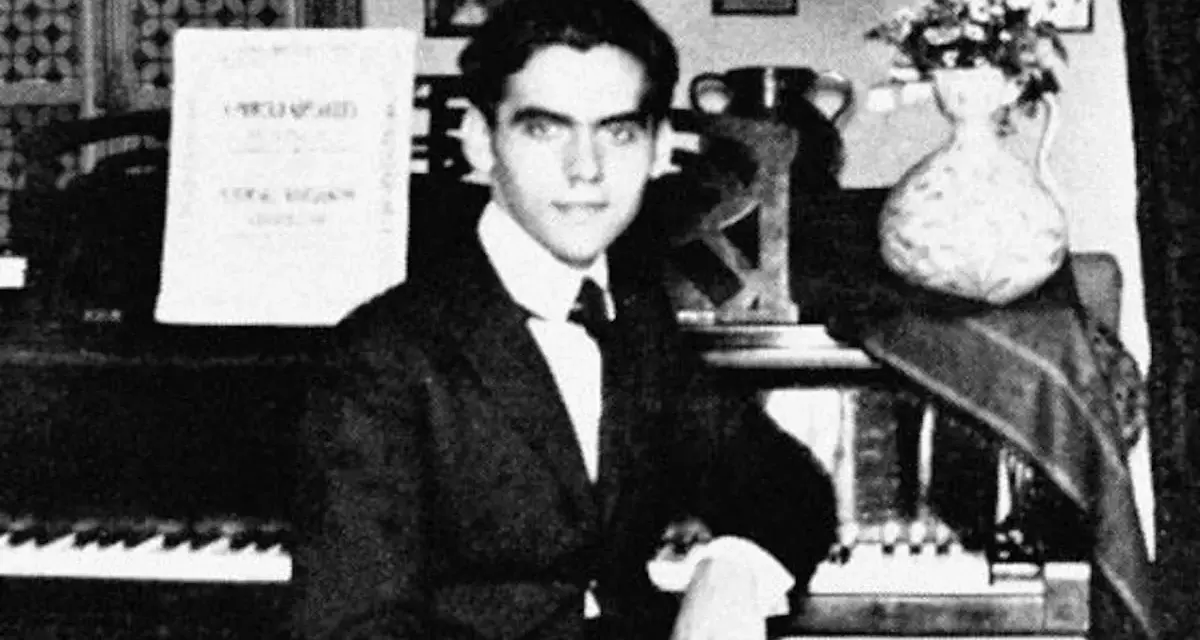Ung man vid piano, kanske Federico García Lorca, med noter och blommor i vas.