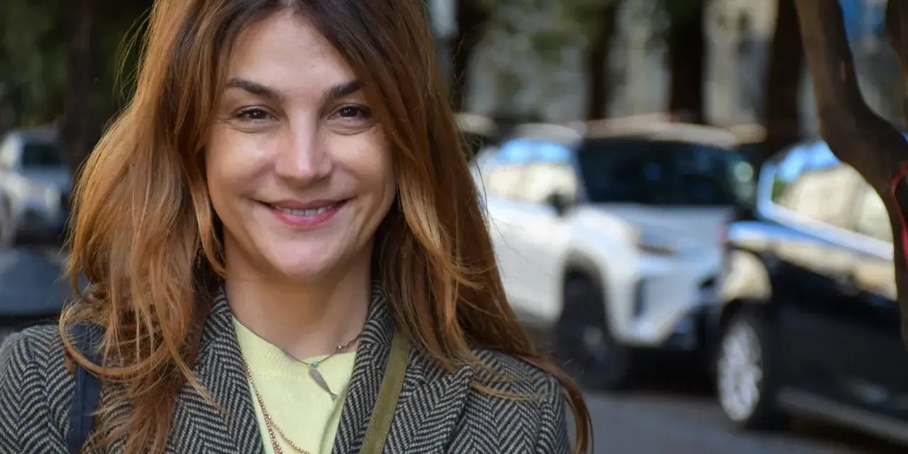 Viola Ardone ler glatt ut mot kameran, klädd i en rutig kavaj och en ljusgul tröja.