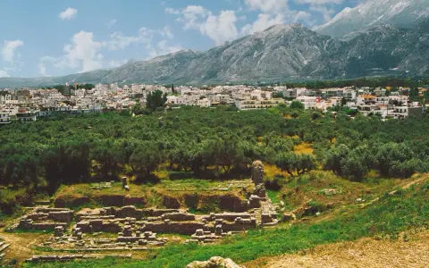 Antika ruiner vid foten av berg, med en stad och olivlundar. En påminnelse om forntida strider mellan sparta och aten.