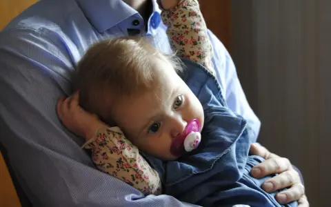 En pappa håller sin lilla dotter, som har en napp i munnen. Bilden känns som en dikt till min dotter.