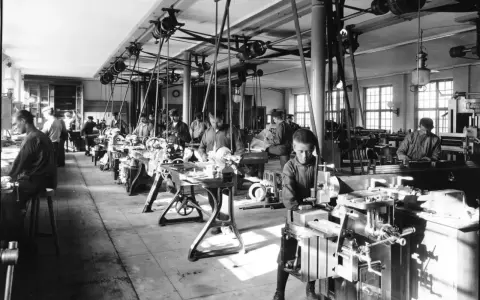 Barnarbete i en verkstad under industriella revolutionen. Pojkar arbetar vid maskiner, en del av den tidiga industrialiseringen.