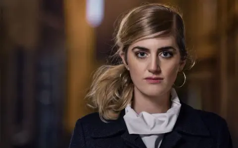 Matilda Voss Gustavsson med blå ögon och hästsvans, bär en mörk kappa och vit krage.