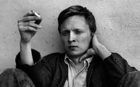 En man med cigarett i handen, Stig Larsson, med handen bakom nacken.