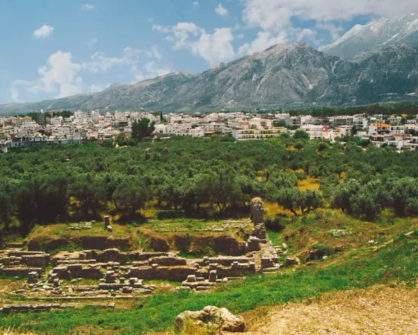 Antika ruiner vid foten av berg, med en stad och olivlundar. En påminnelse om forntida strider mellan sparta och aten.