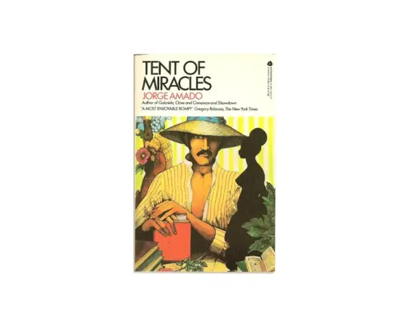 Omslag till "Tent of Miracles" av Jorge Amado. En man med hatt och mustasch sitter vid ett bord med böcker.