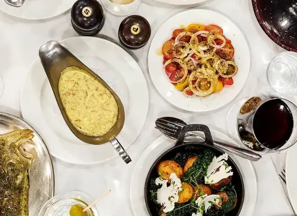 En festmåltid på Sture Hof: grillad biff, hel fisk, pasta med gröna ärtor, potatis och grönsaker, samt en tomat- och löksallad.