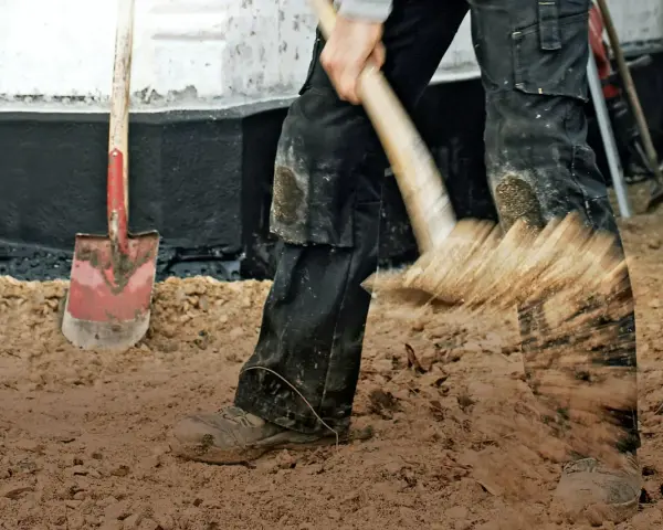 Arbetare gräver med spade, en synonym för att betona vikten av grundläggning.