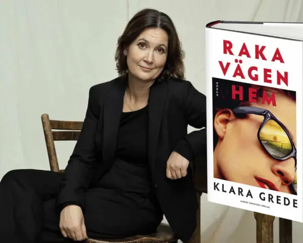 Klara Grede, författaren till "Raka vägen hem", sitter i en stol bredvid sin bok.