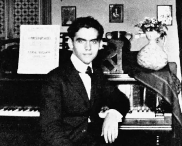 Ung man vid piano, kanske Federico García Lorca, med noter och blommor i vas.