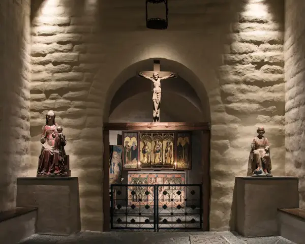 En kyrka från medeltiden med en krucifix, helgonstatyer och altarskåp.