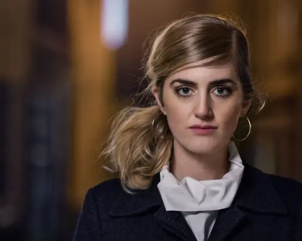 Matilda Voss Gustavsson med blå ögon och hästsvans, bär en mörk kappa och vit krage.
