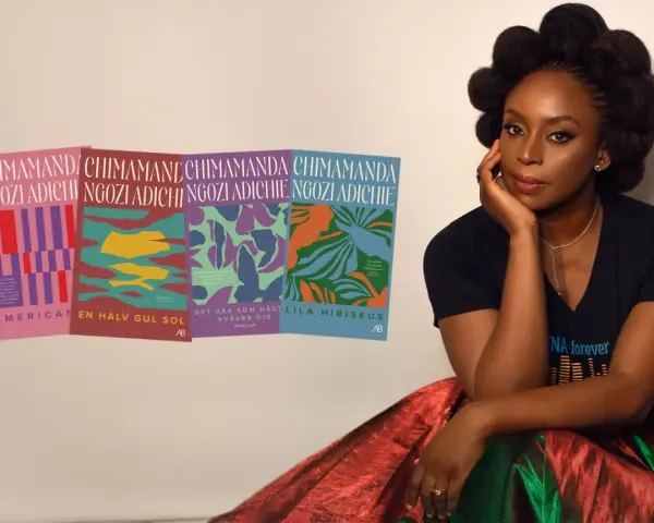 Chimamanda Ngozi Adichie sitter bredvid sina böcker, inklusive "Lila hibiskus".