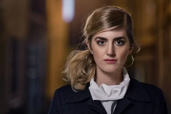 Matilda Voss Gustavsson med blå ögon och hästsvans, bär en mörk kappa och vit krage.