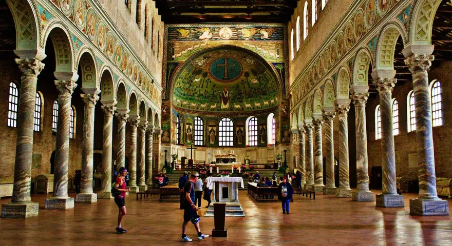 Interiör av en basilika med mosaiker. En man som heter Dante går förbi en pelarrad.