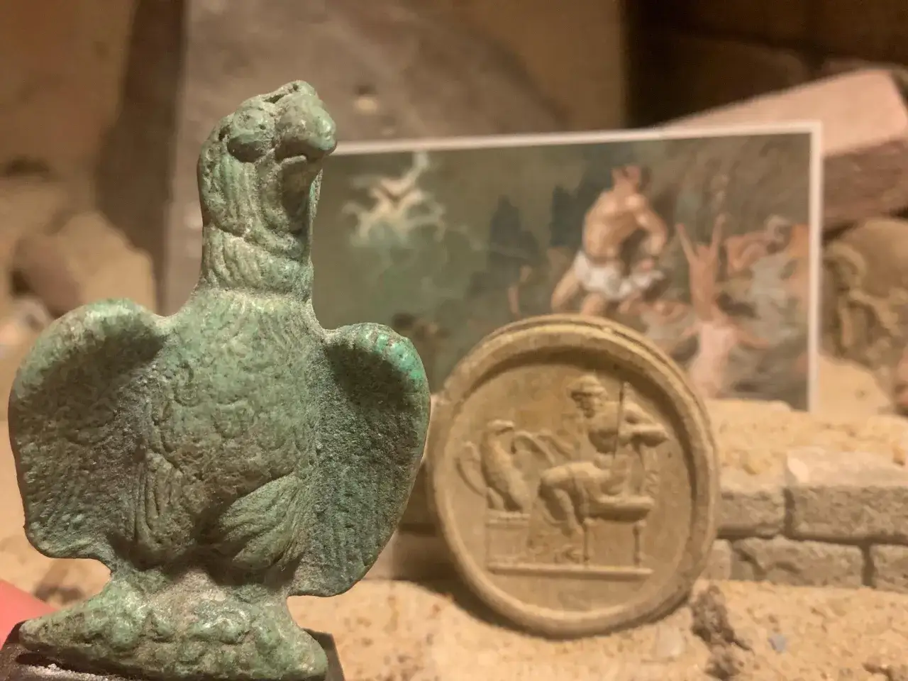 En brons&ouml;rn och en medaljong med en sittande figur. Kanske en ledtr&aring;d till vem &auml;r Zeus, himlens och &aring;skans gud.